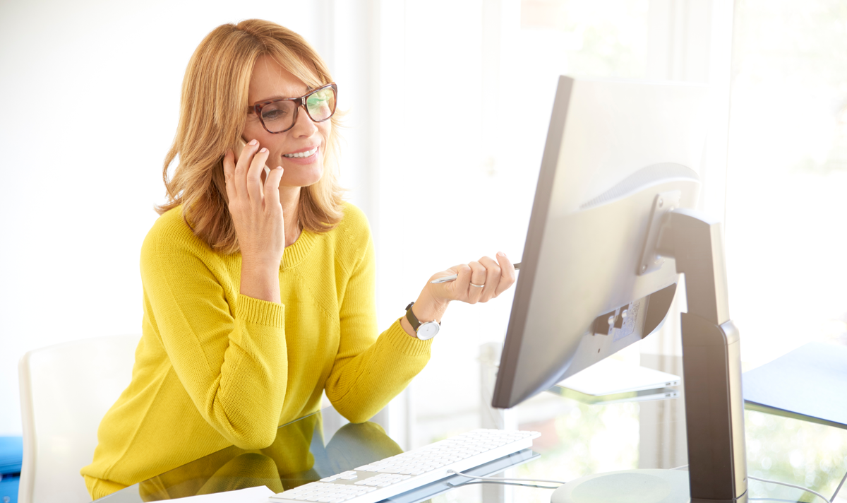 Woman at desk describing computer issue.